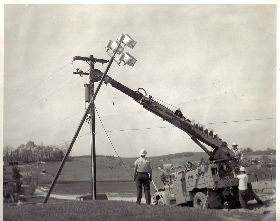A black and white photo of a truck with a crane attached to it
