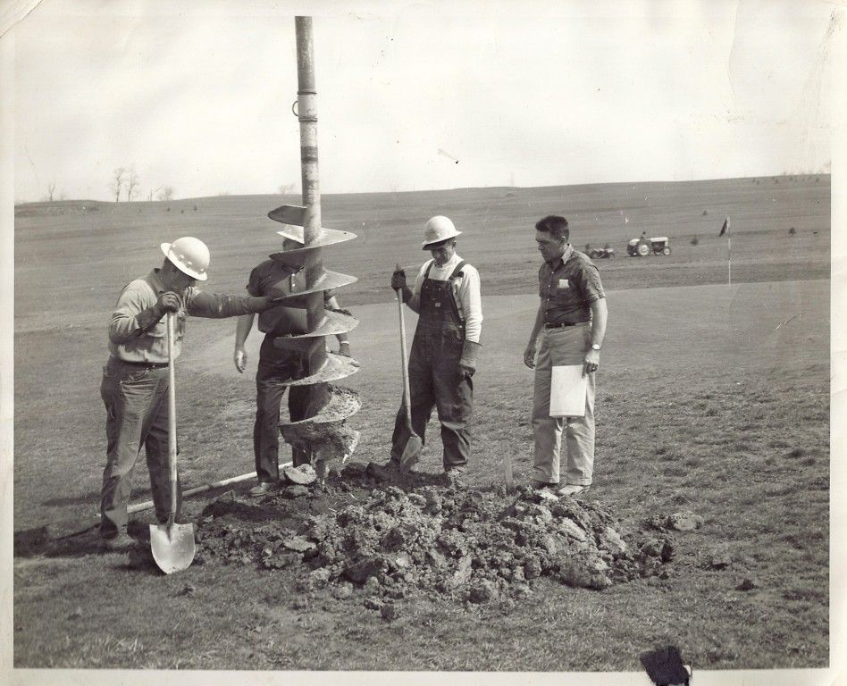 A group of men are working on a hole in the ground