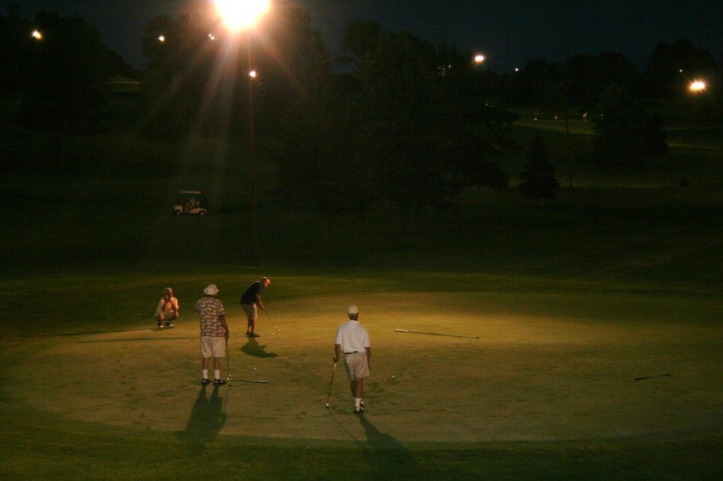 A group of people are playing a game of baseball at night