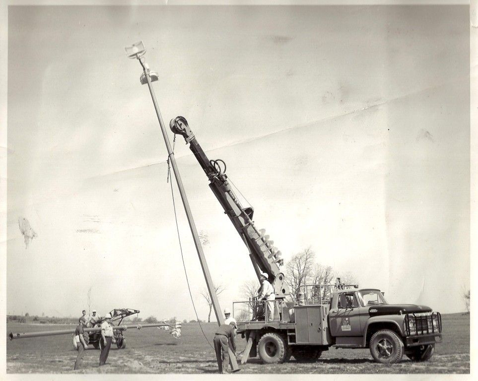 A black and white photo of a truck with a crane attached to it