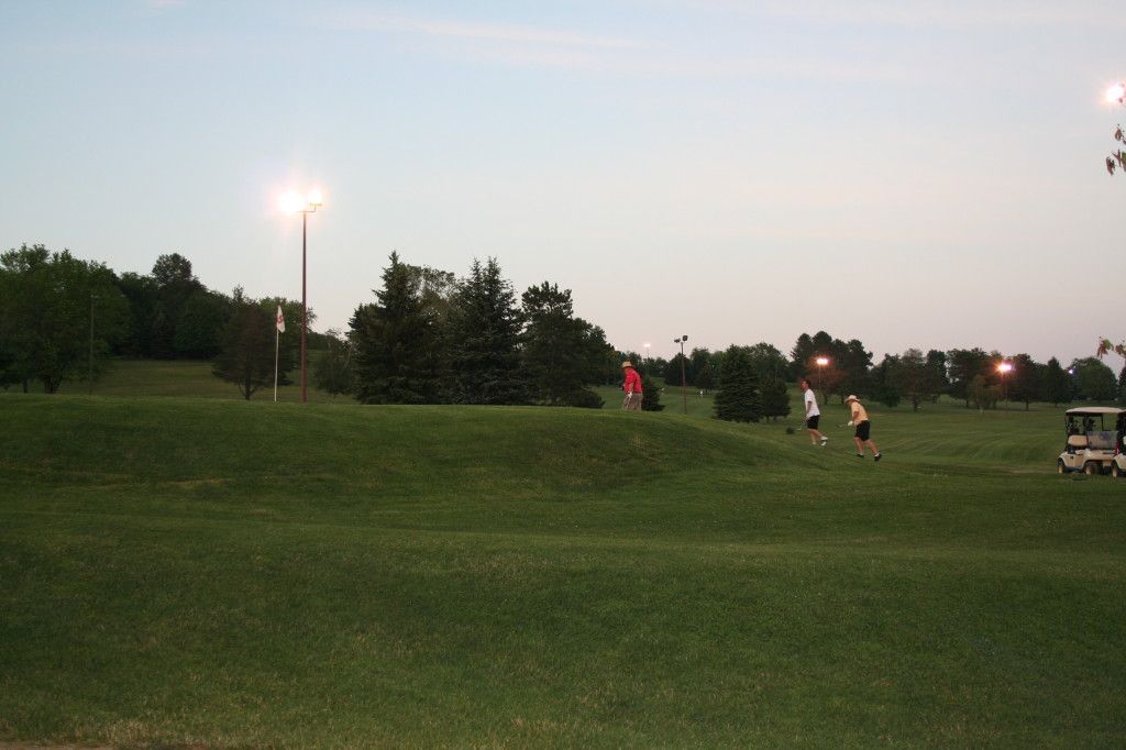 A group of people are playing golf on a golf course at night.
