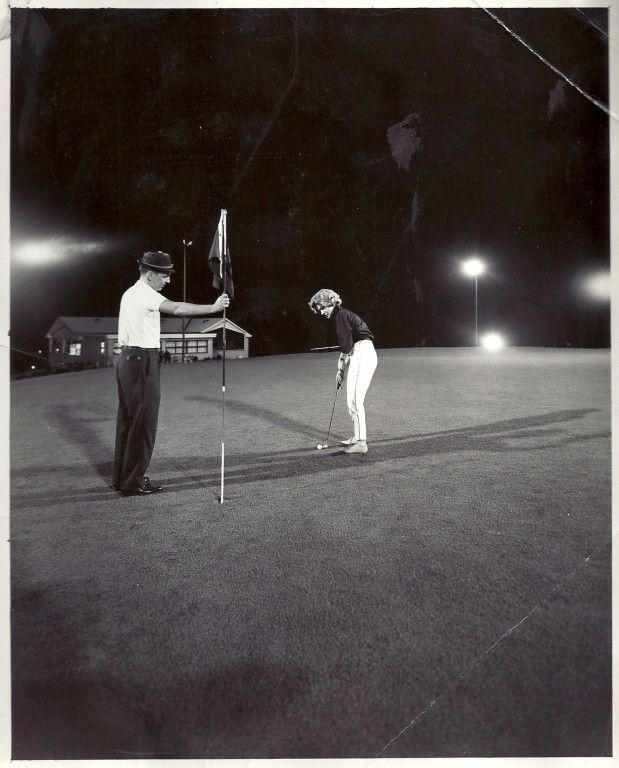 A black and white photo of two people playing golf
