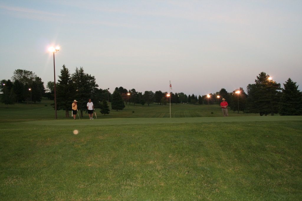 A group of people are running on a golf course at night.