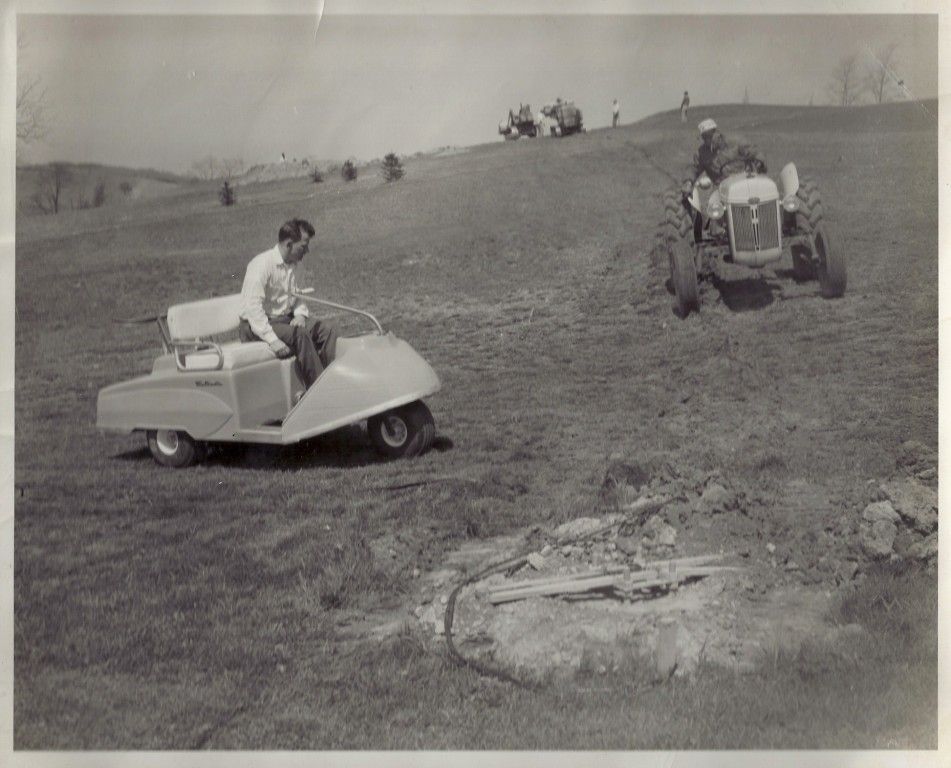 A black and white photo of two men riding lawn mowers