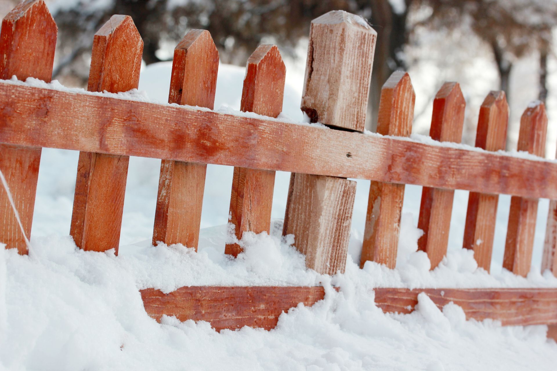 A wooden fence is covered in snow on a snowy day