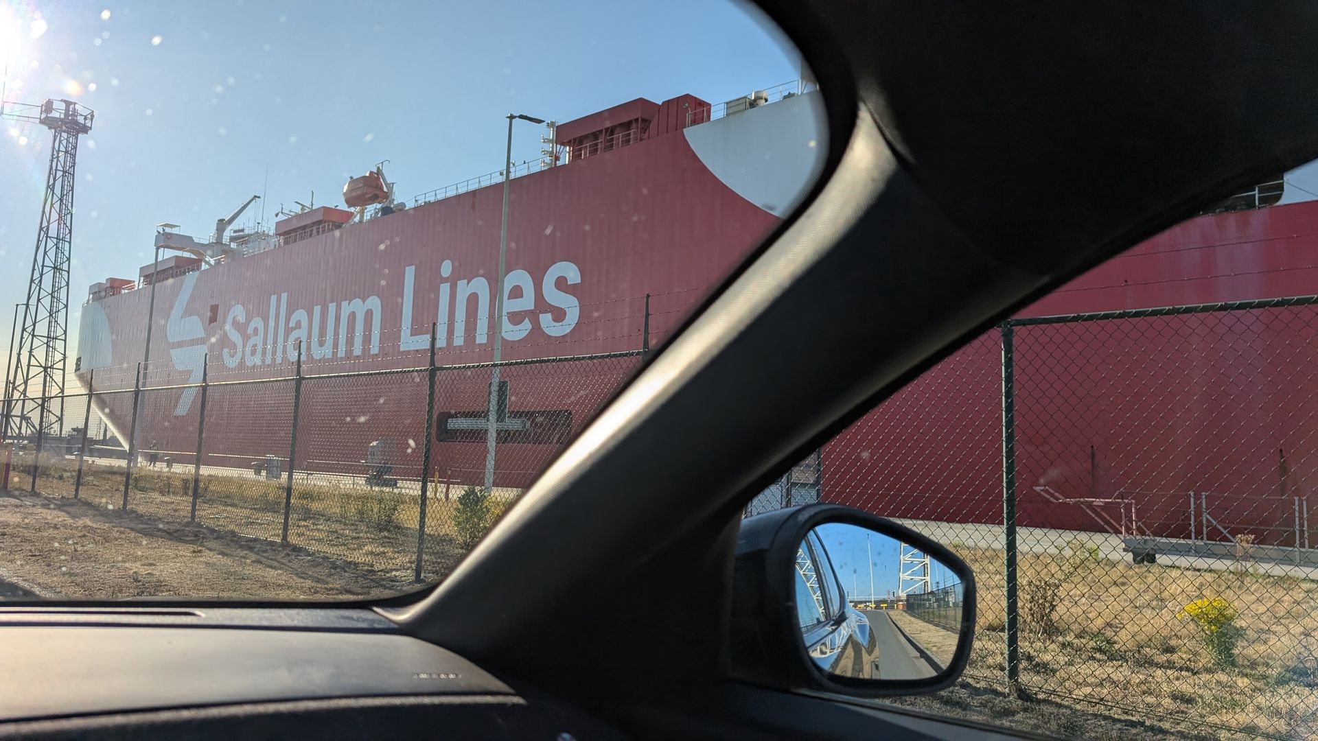 Red cargo ship from Saltenum Lines seen from inside a car at a port.