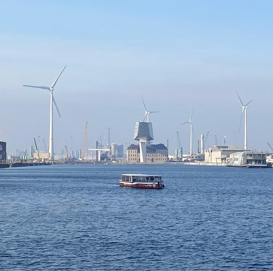 Harbor with wind turbines and a small boat on calm blue water under a clear sky