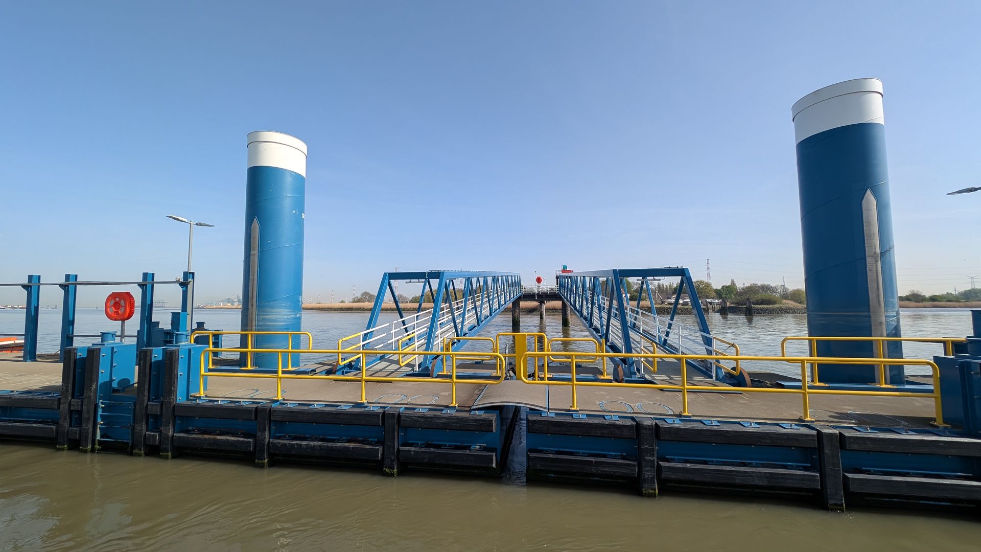 Floating blue-and-yellow dock with railings on a calm waterfront under a clear sky