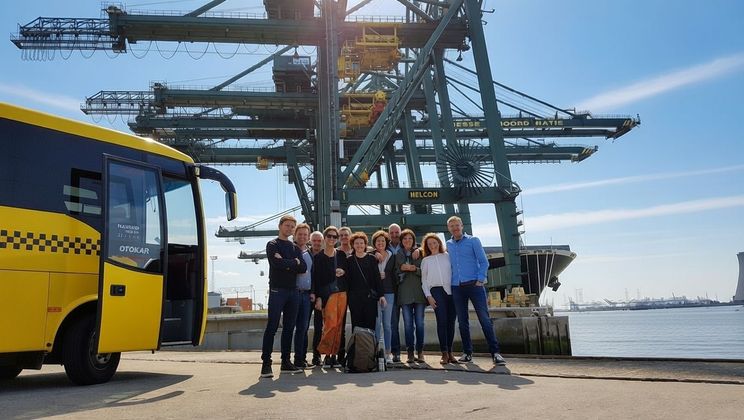 Group of people posing in front of large port cranes.