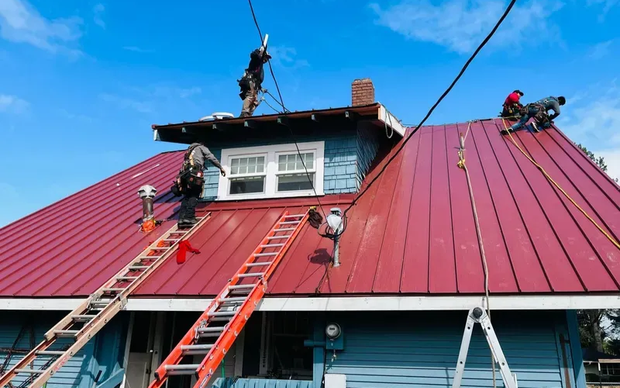 Red standing seam metal roof installation on residential home