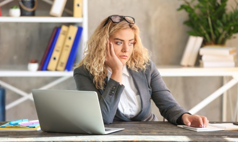 professional woman at office desk looking disinterested