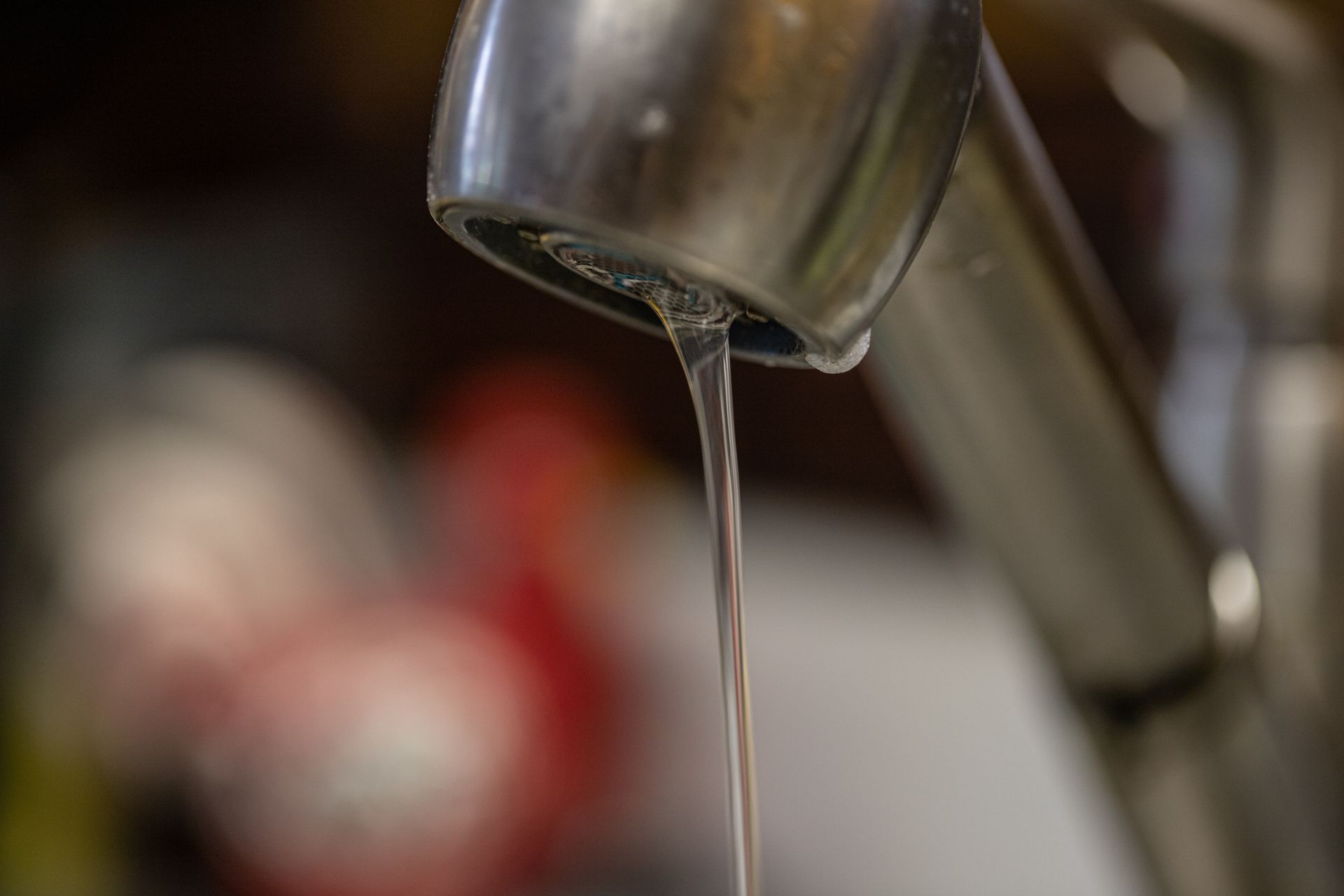 Close-up of a faucet releasing a thin stream of water in a kitchen sink area.