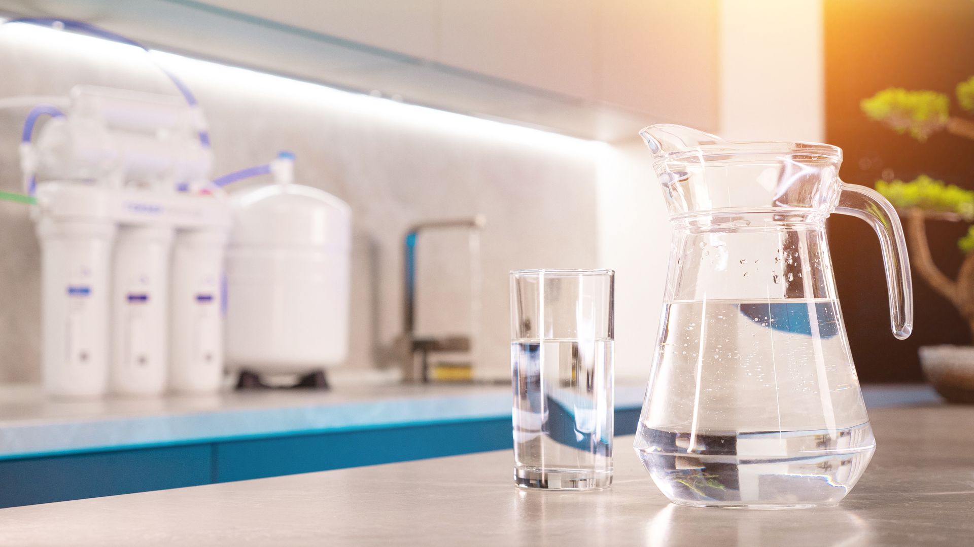 Water system treatment with a home filtration system, pitcher, and glass of water.