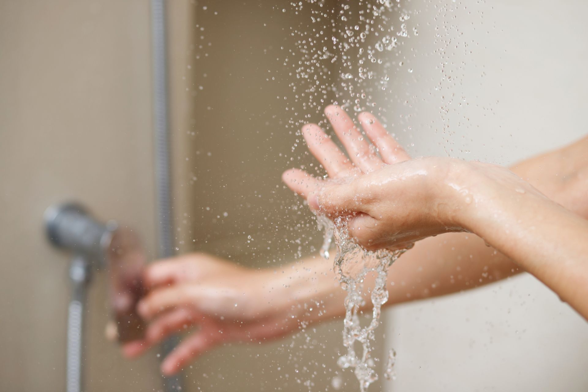 A woman checks the water temperature with her hand before showering A woman checks the water temperature with her hand before showering