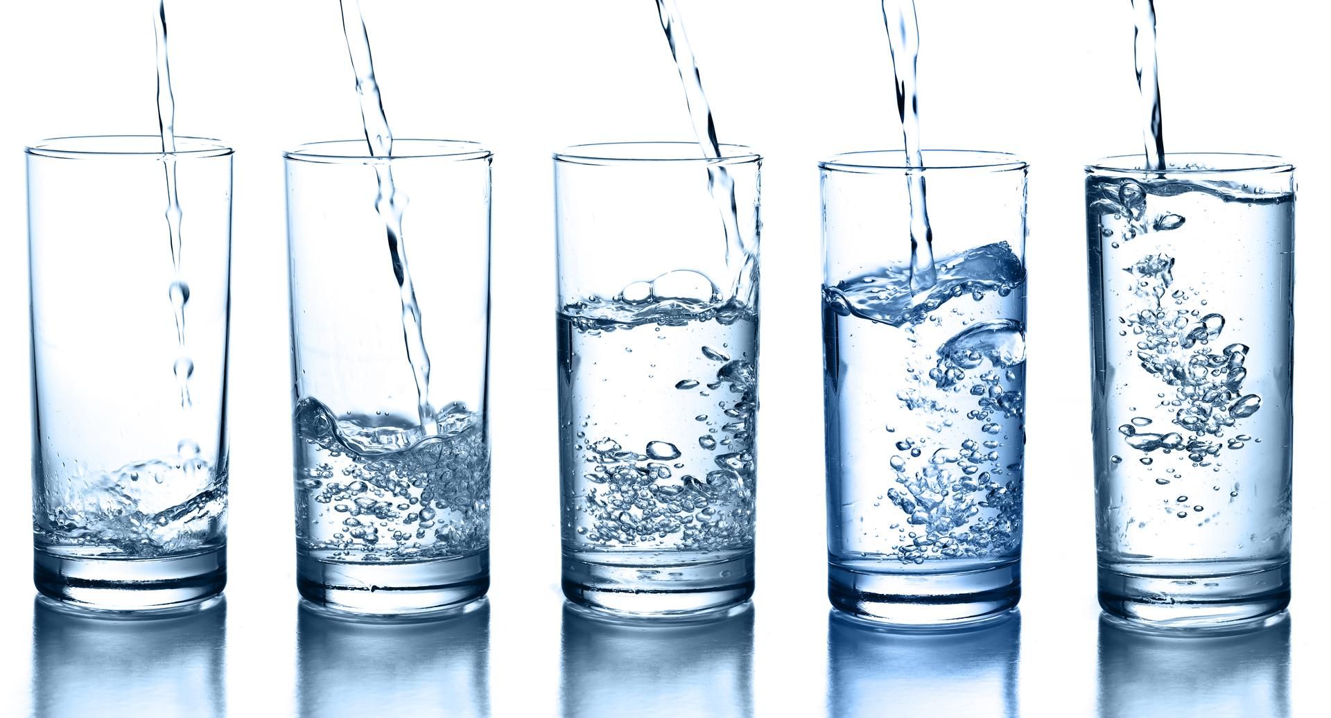 Water is being poured into a row of glasses