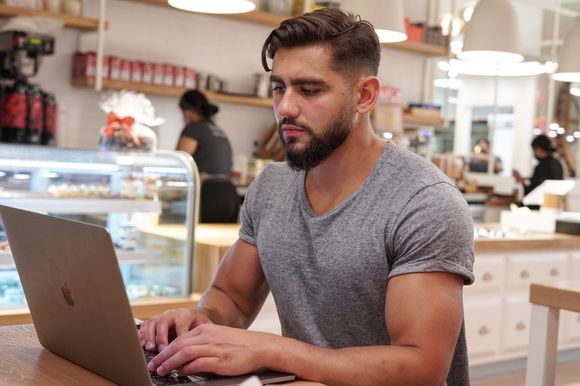 A man is sitting at a table using a laptop computer.