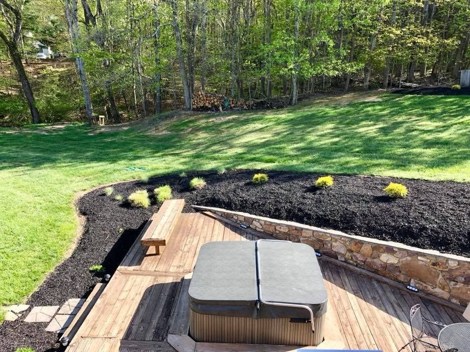 Patio with outdoor sofa and planters overlooking a green lawn and wooded backyard