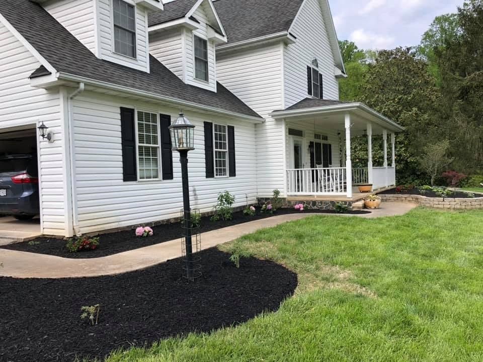 White house with black shutters, front porch, and newly landscaped yard with fresh mulch and grass