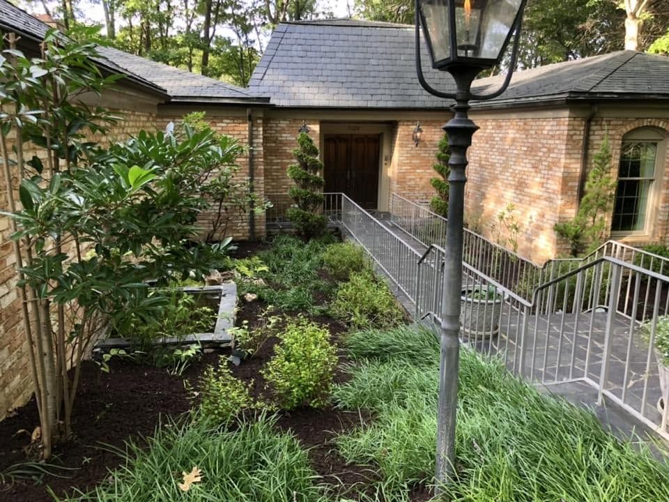Brick courtyard garden with black lamp post and metal railing leading to a doorway
