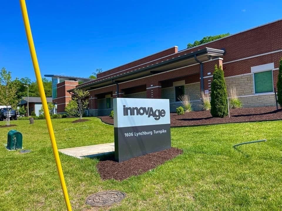 InnovAge sign on a lawn outside a brick building under a bright blue sky