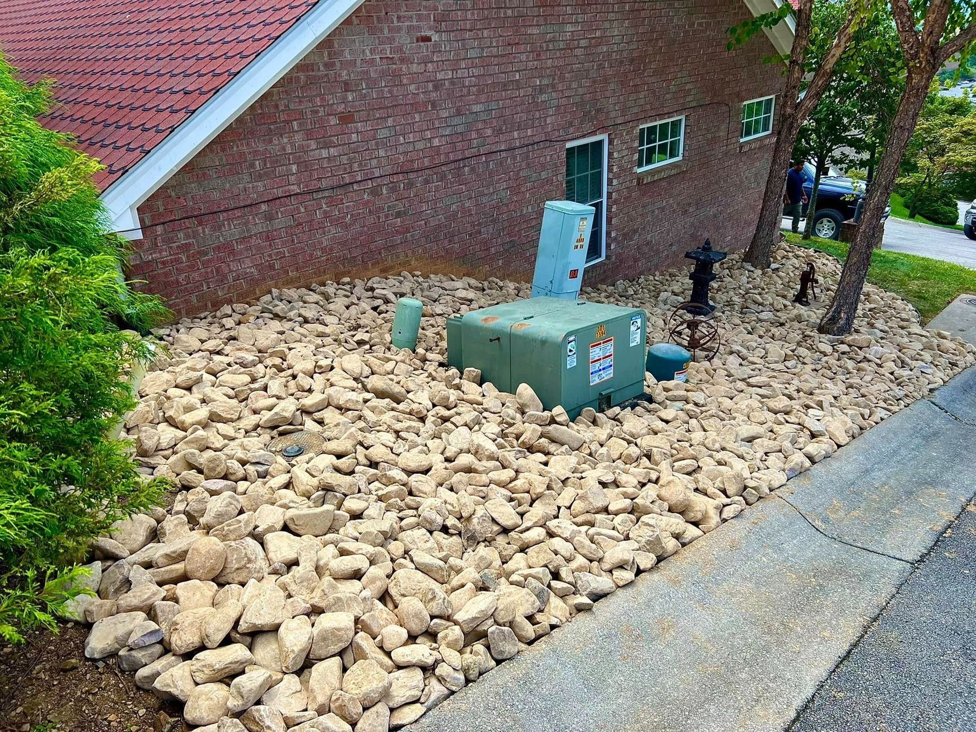 Rock-covered utility area beside a brick building with green electrical boxes and a small fire hydrant