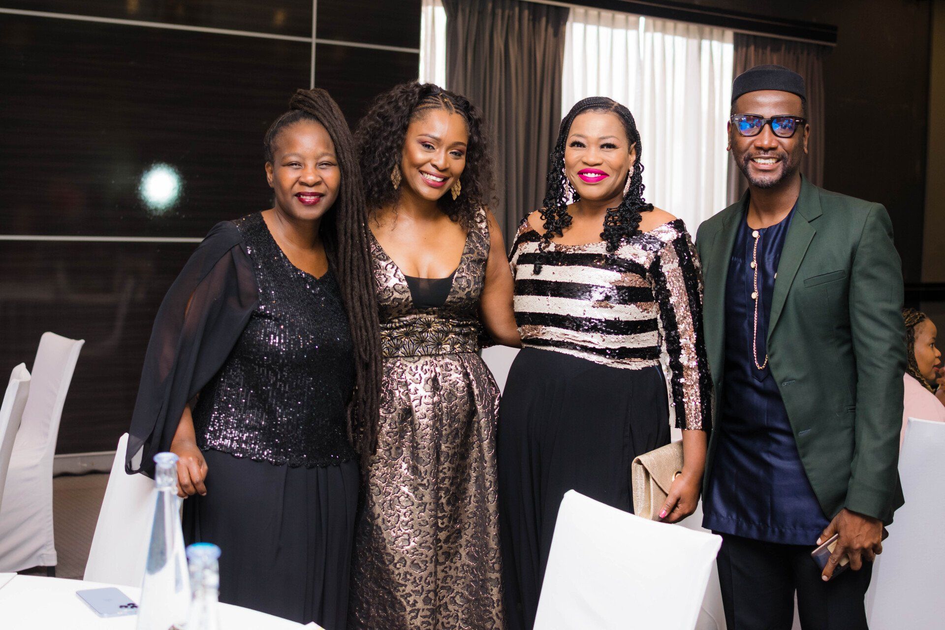 three professional woman and one man posing for a photo at an evening event