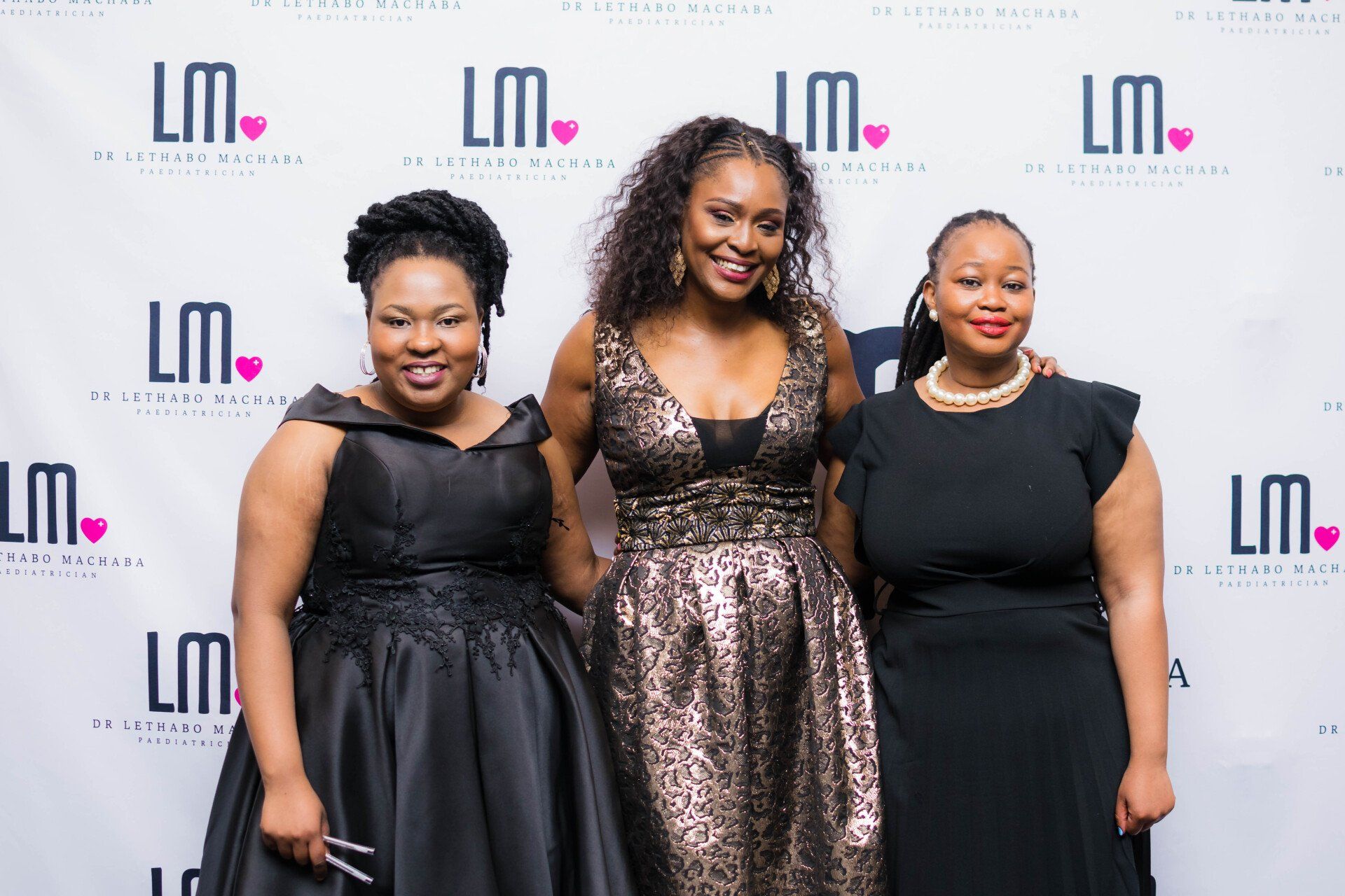 three professional woman posing for a photo at an evening event
