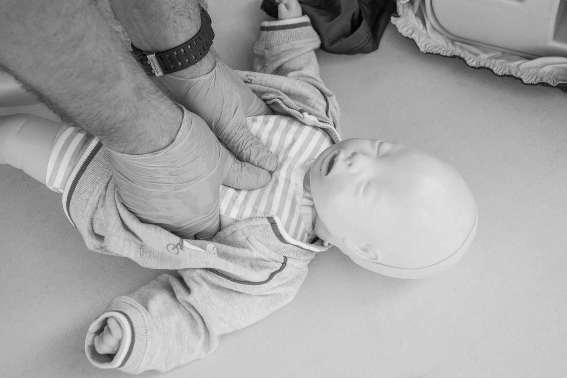 A man is holding a baby mannequin on a yellow mat.
