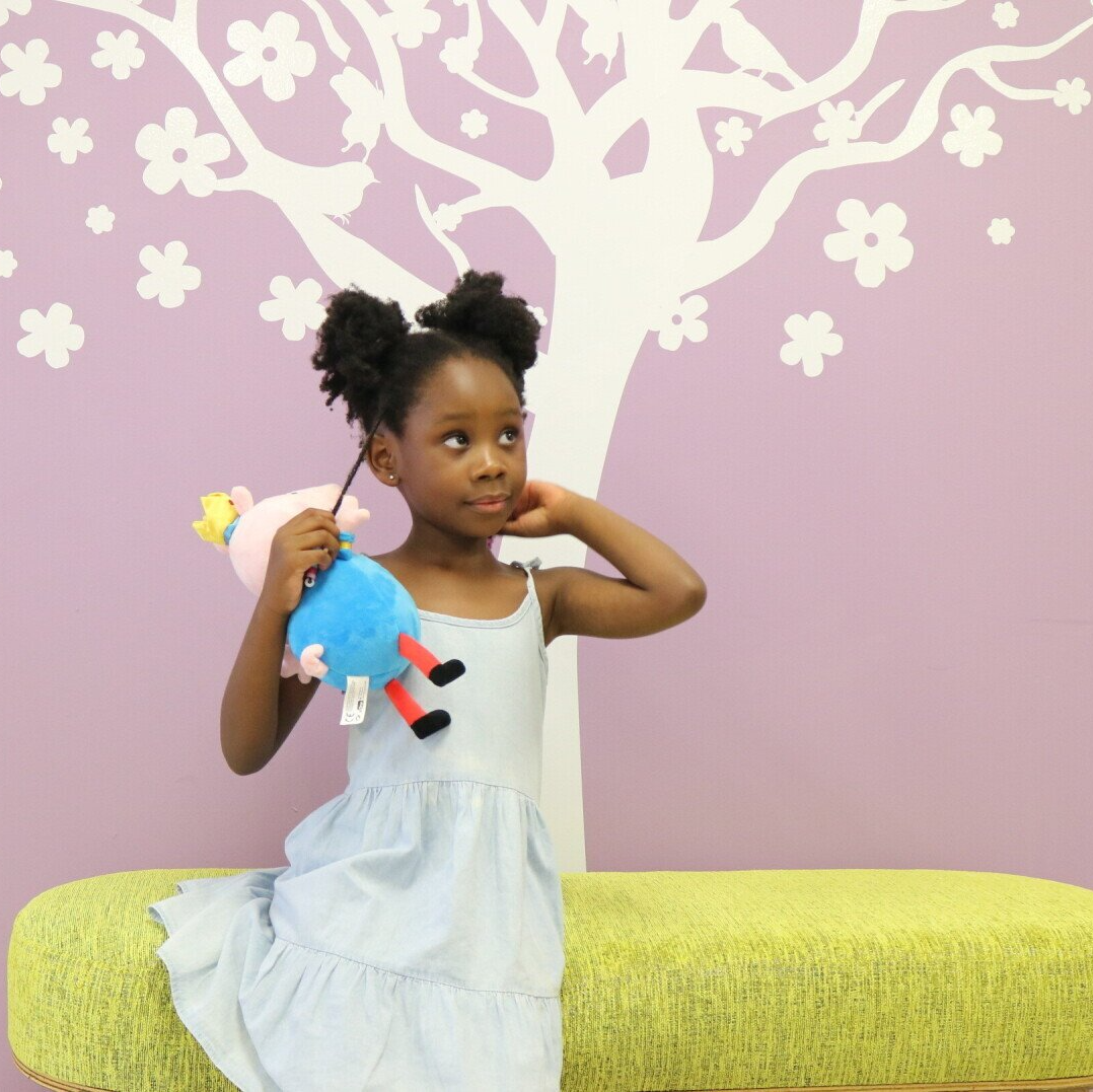 young girl in a white dress holding a soft toy