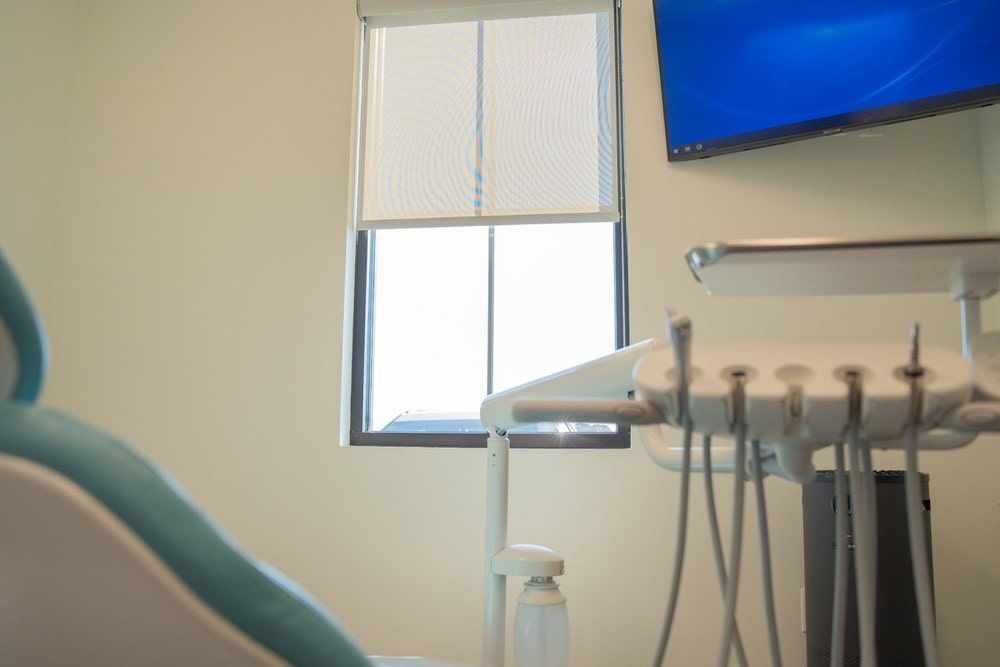 A dental office with a dental chair and a television on the wall.