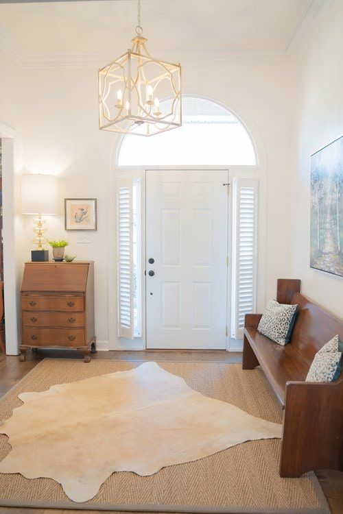 A living room with a couch and a rug in front of a white door with white shutters covering the windows.