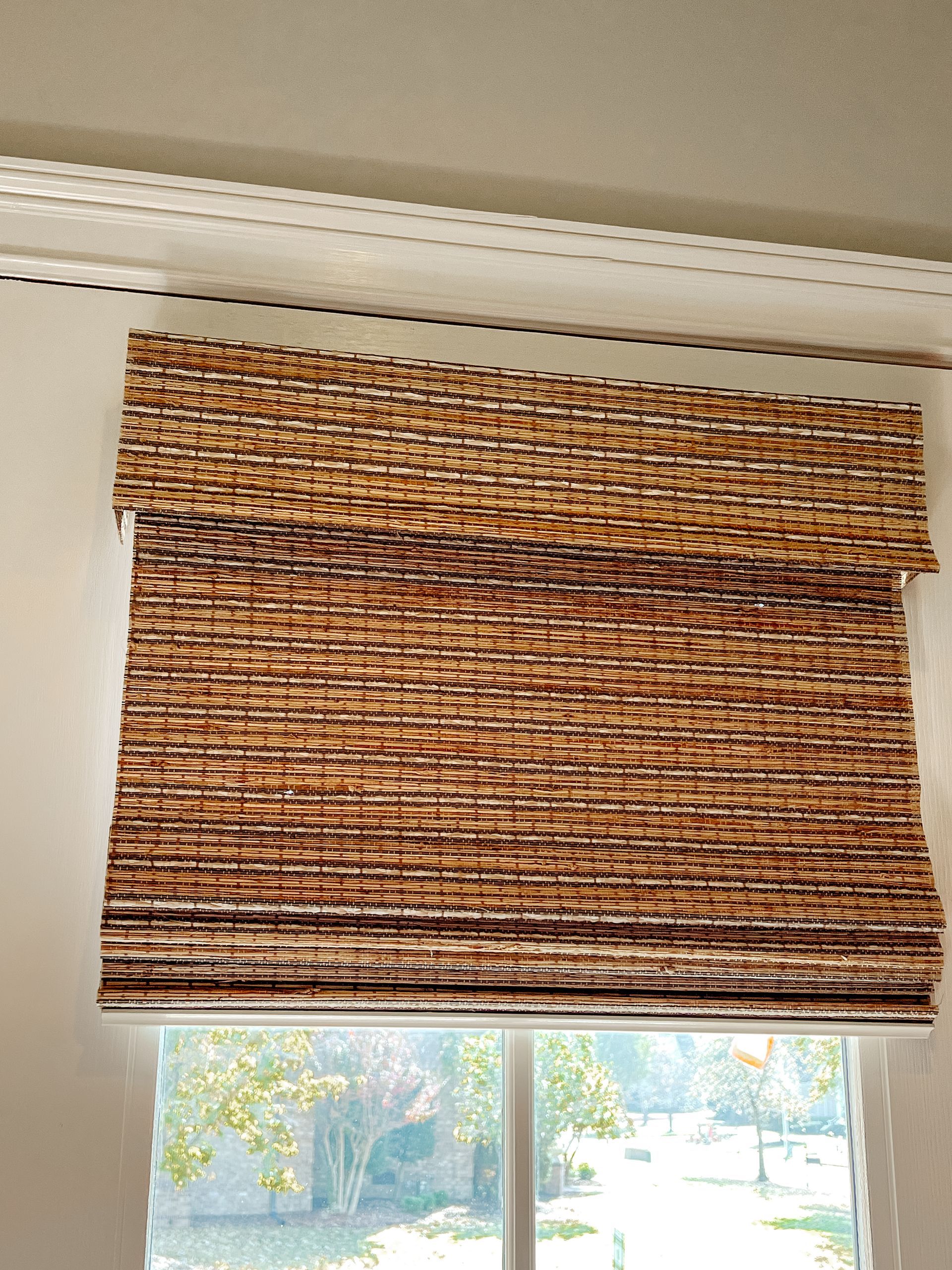 A window with a natural woven shade on it.
