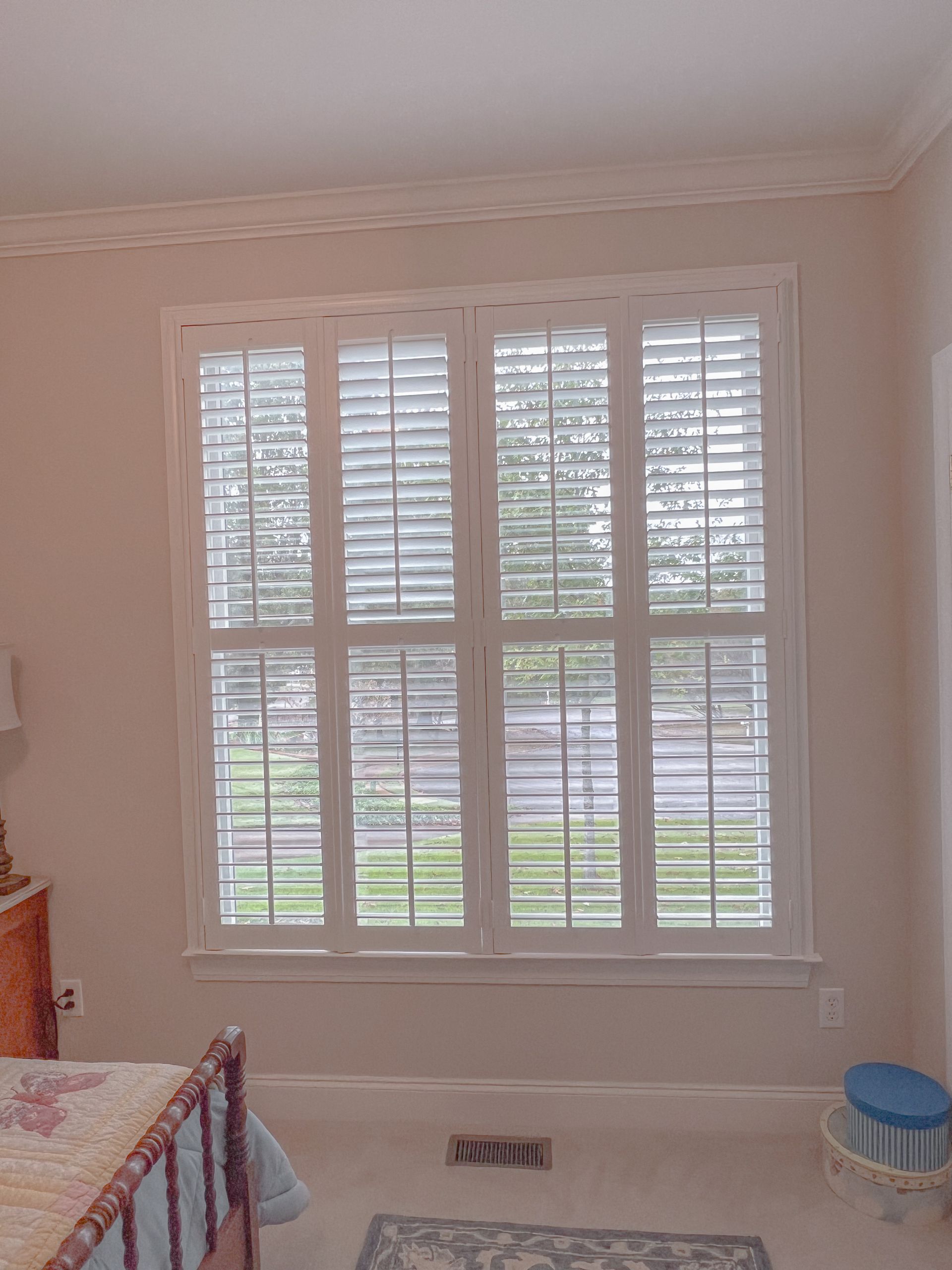 A bedroom with a bed and a window with shutters on it.