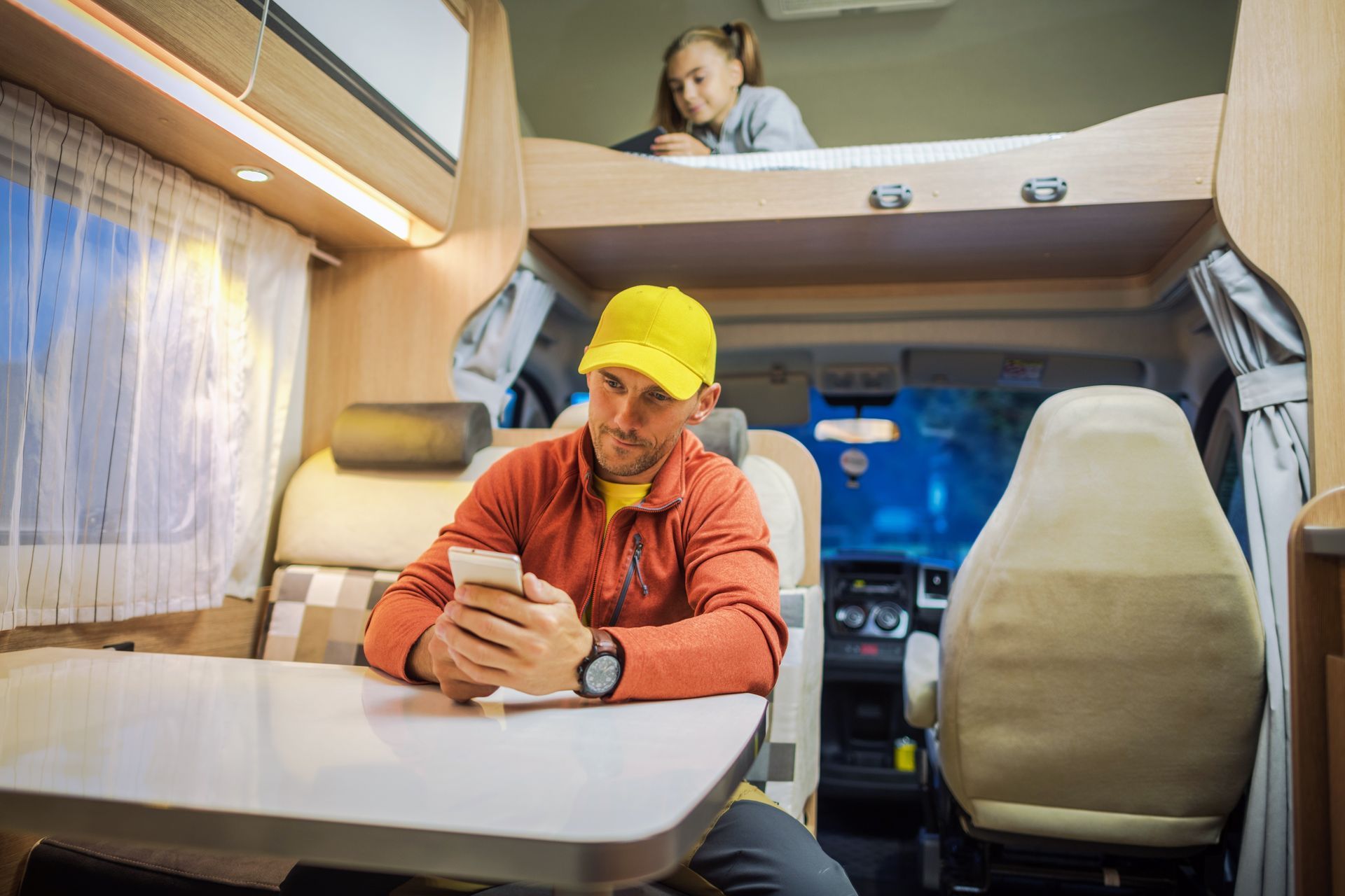 A man is sitting at a table in a rv looking at his cell phone.