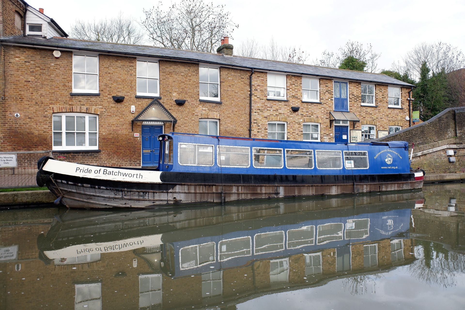 A blue boat is docked in front of a brick building