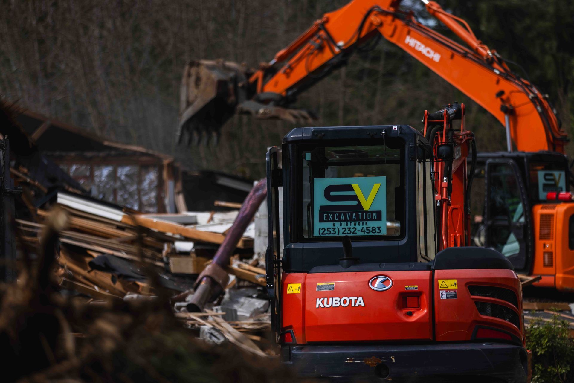 A red kubota excavator is being used to demolish a building.