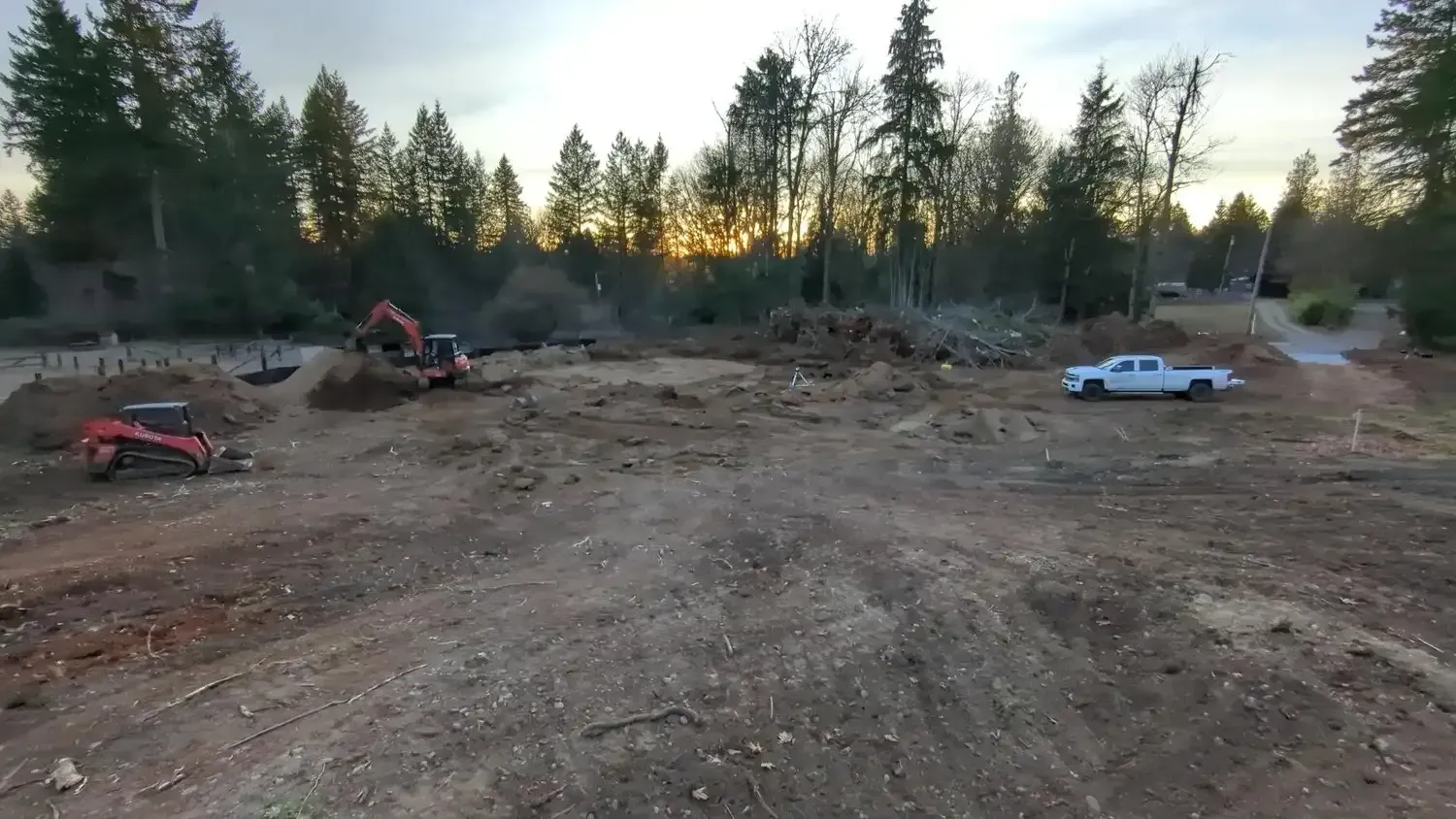 A white truck is parked in the middle of a dirt field.