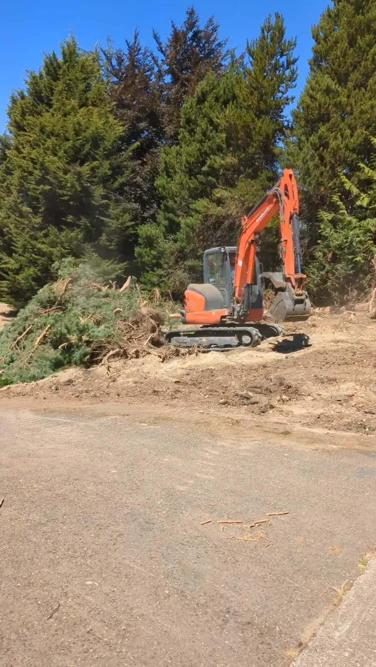 A large orange excavator is sitting in the middle of a dirt field.