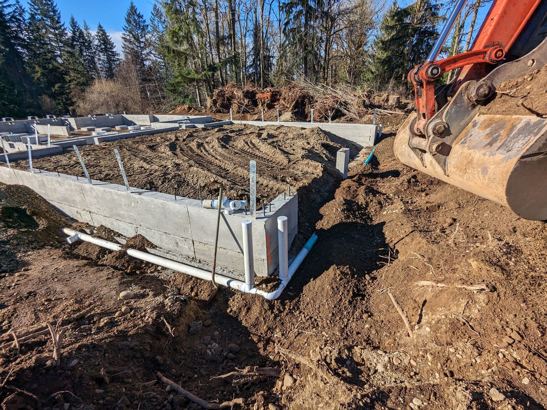 A bulldozer is digging a hole in the dirt next to a concrete wall.
