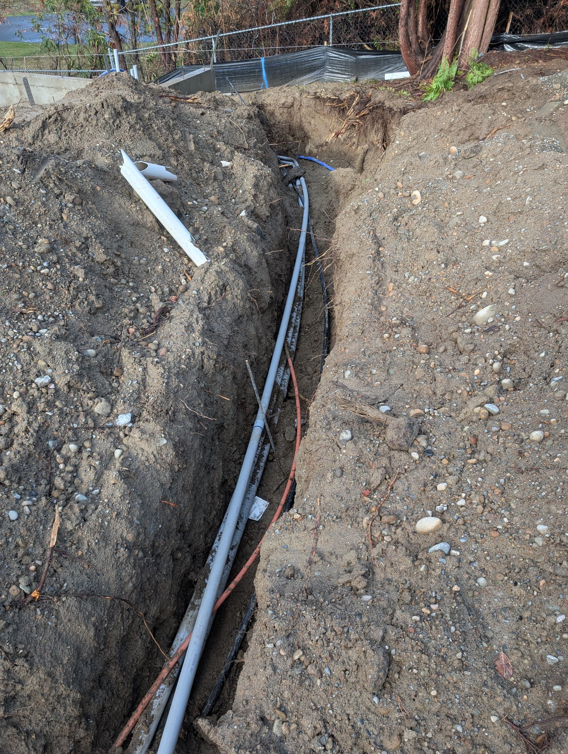A pipe is being installed in a trench in the dirt.