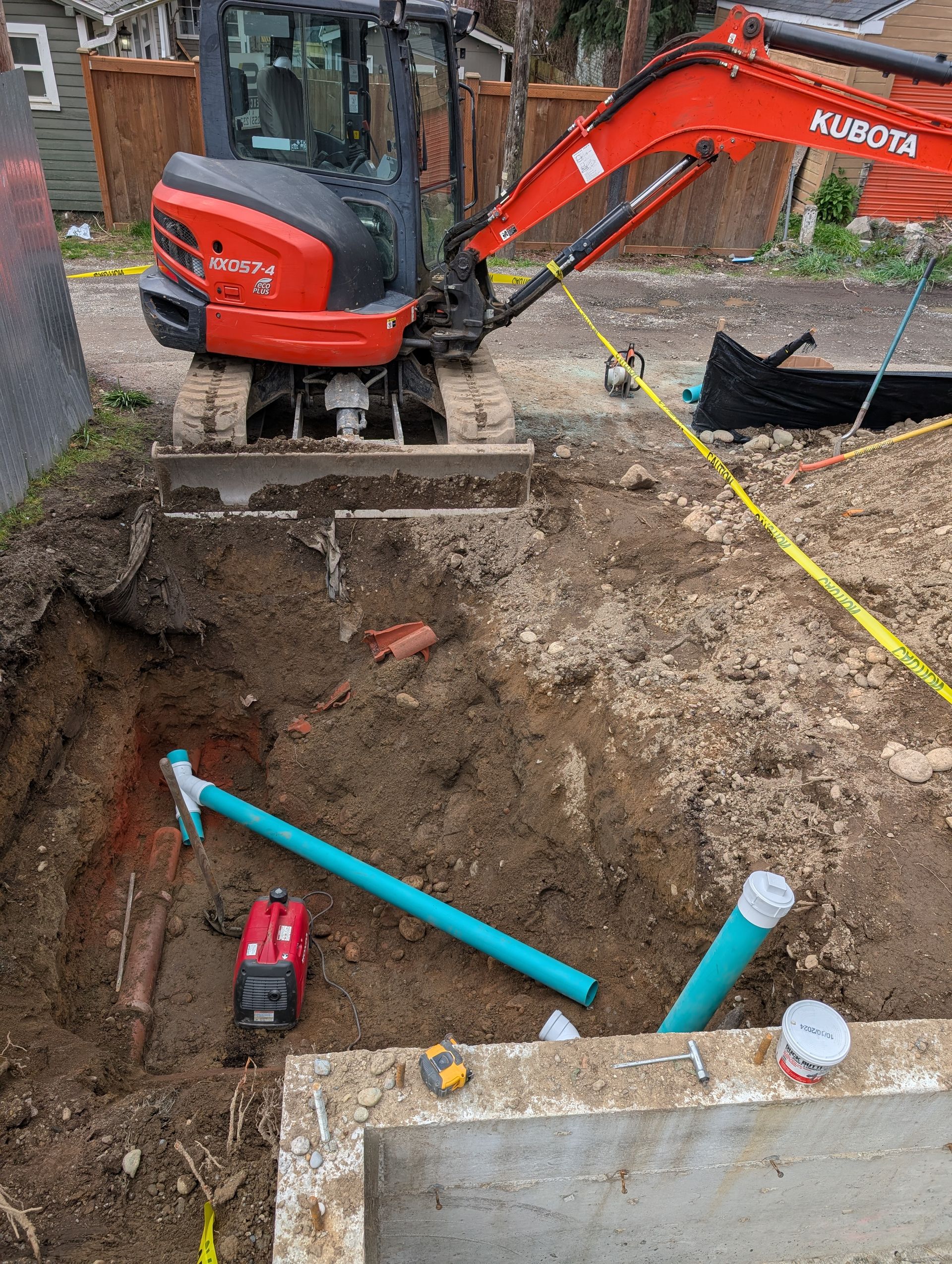 A red and black excavator is digging a hole in the ground.