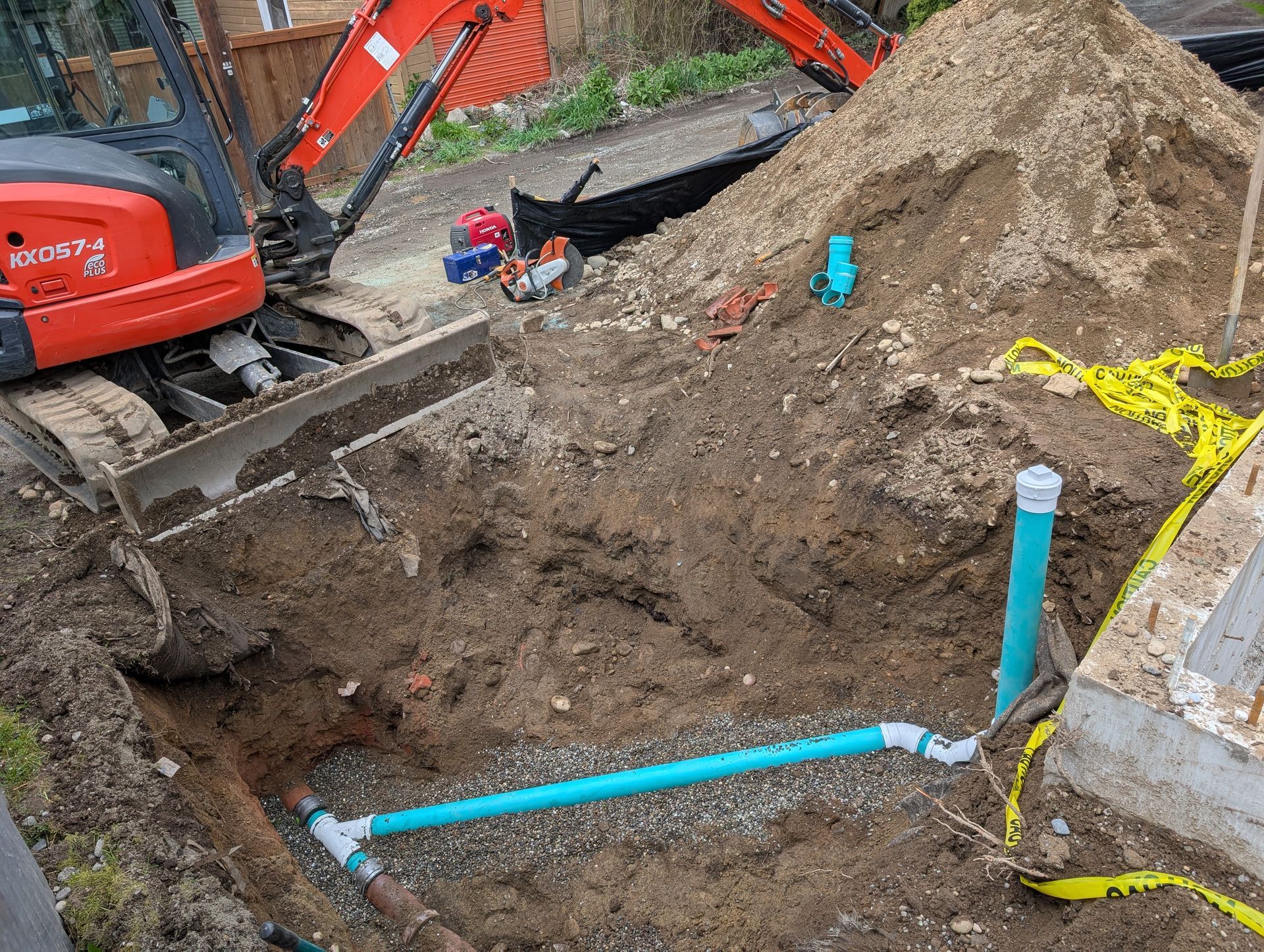 An excavator is digging a hole in the ground next to a pile of dirt.
