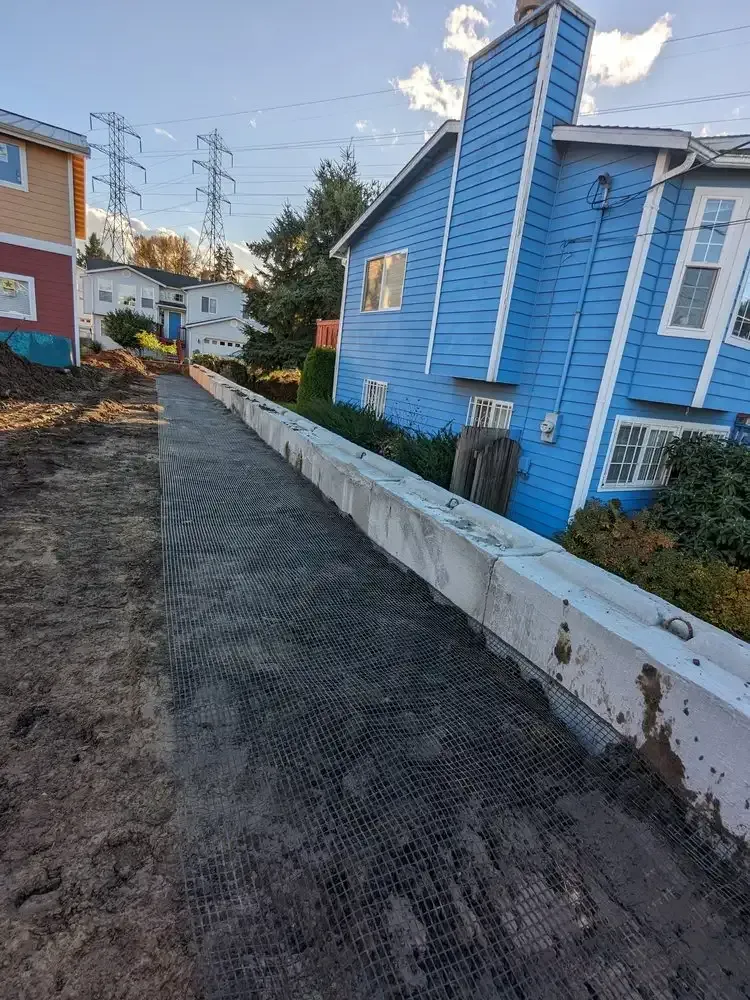 A blue house is being built next to a concrete wall.
