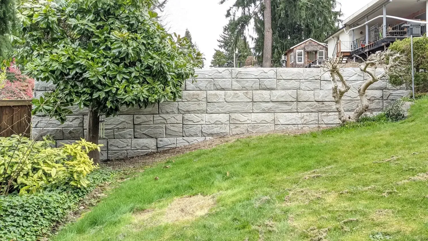 There is a stone wall in the middle of a lush green yard.