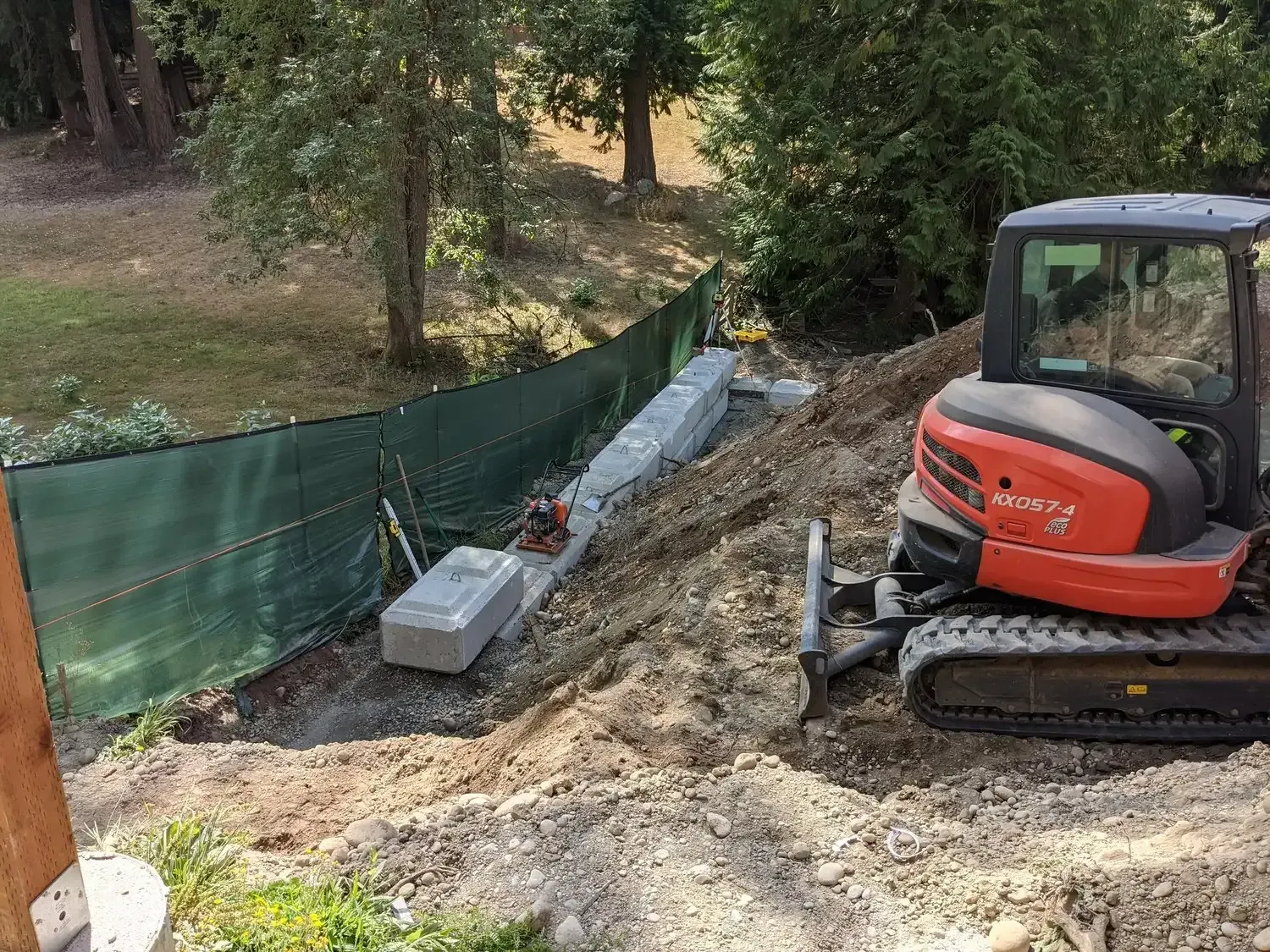 A small red and black excavator is sitting on top of a dirt hill.