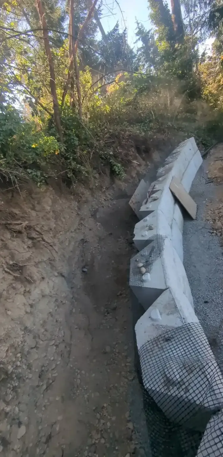 A concrete wall is being built on the side of a dirt road.