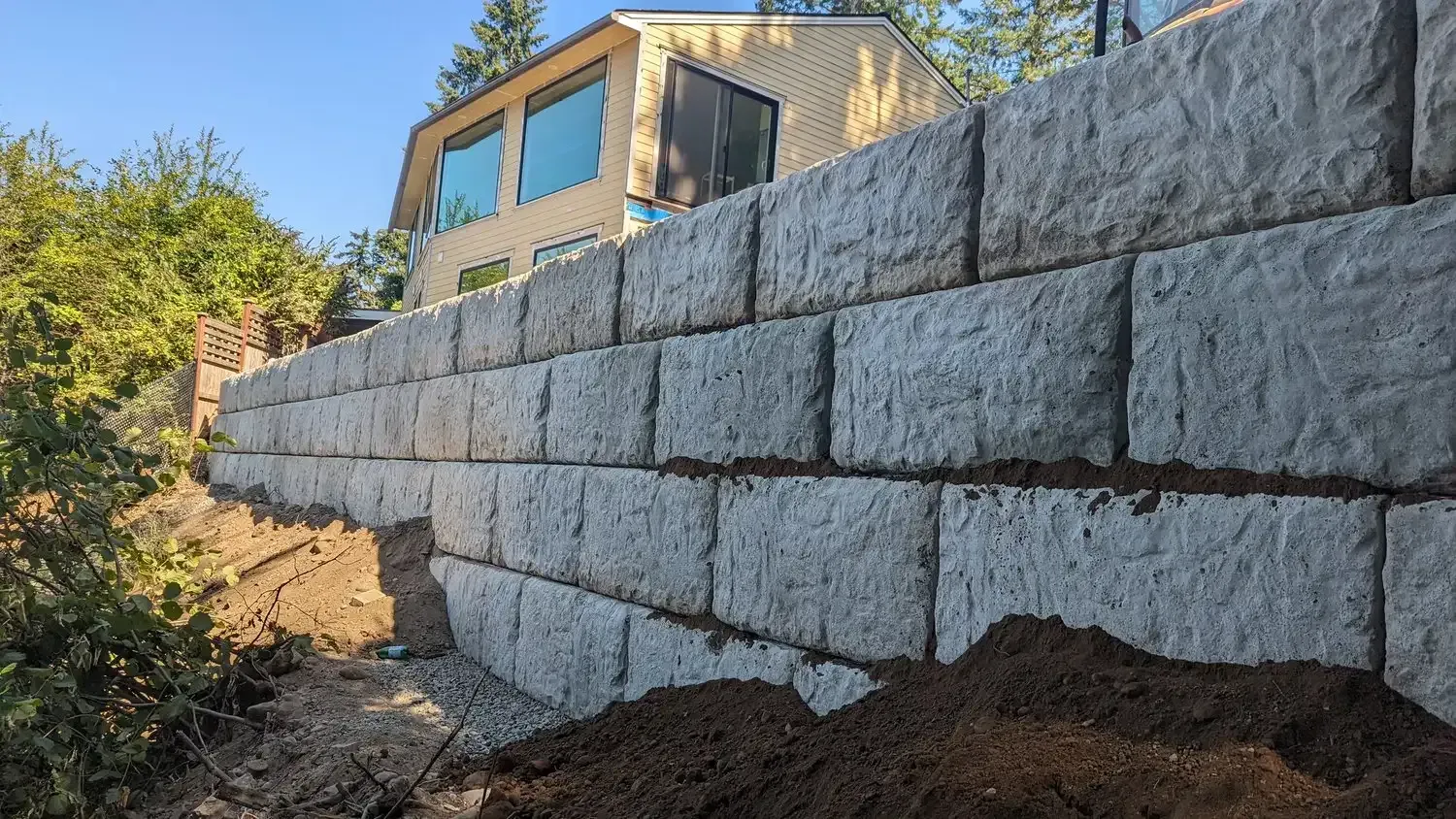 A large brick wall is being built in front of a house.