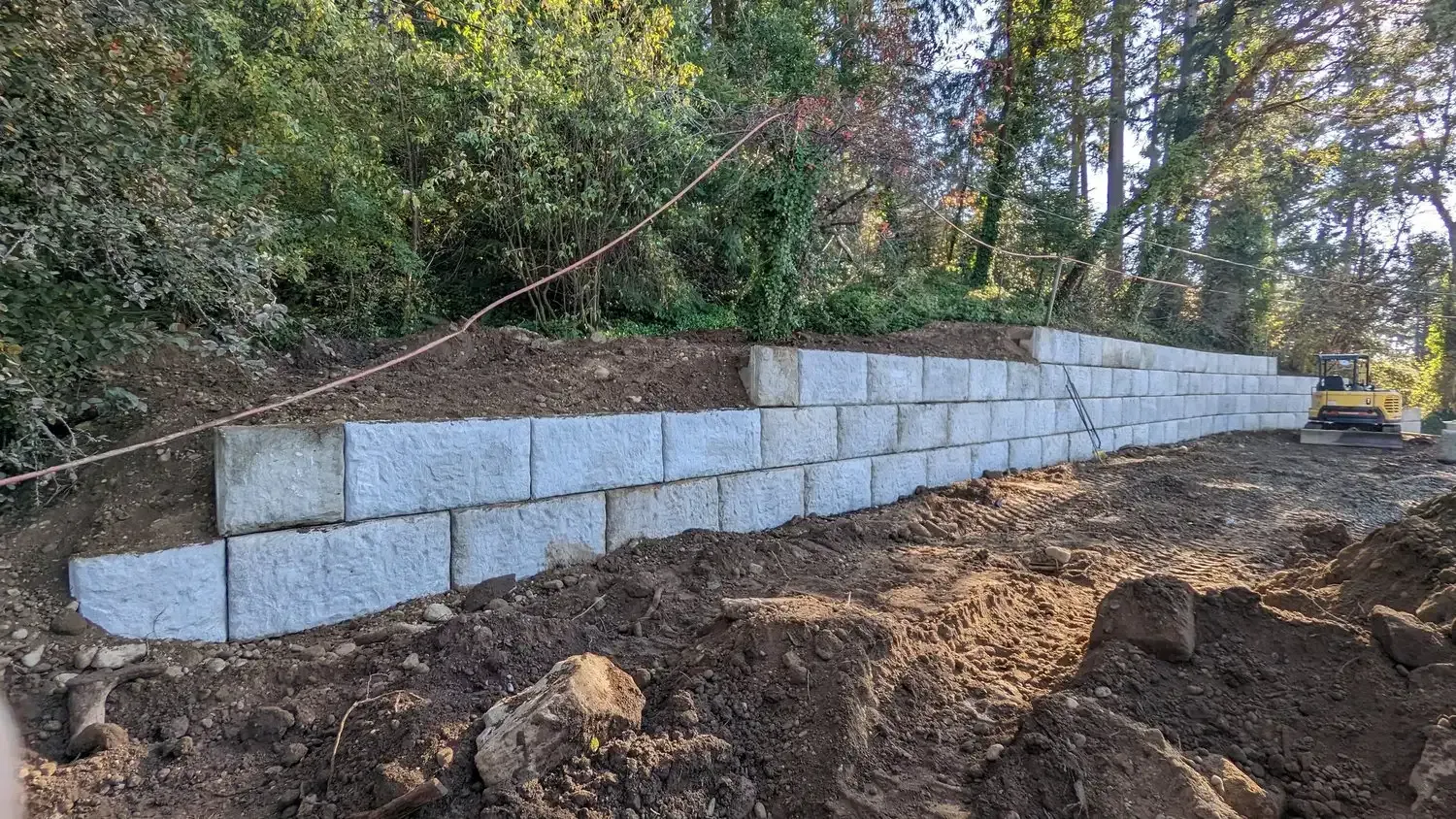A large concrete wall is being built in the middle of a dirt field.