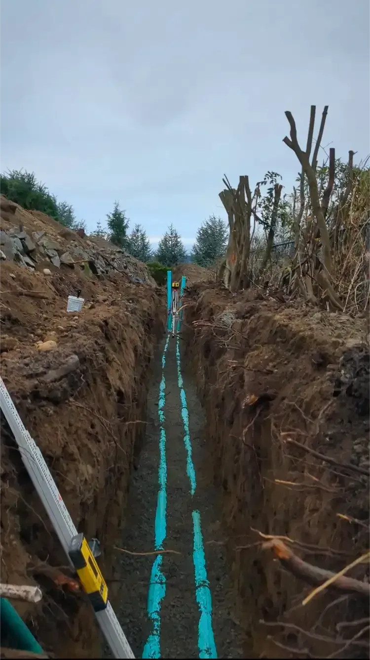 A blue pipe is being installed in a trench.