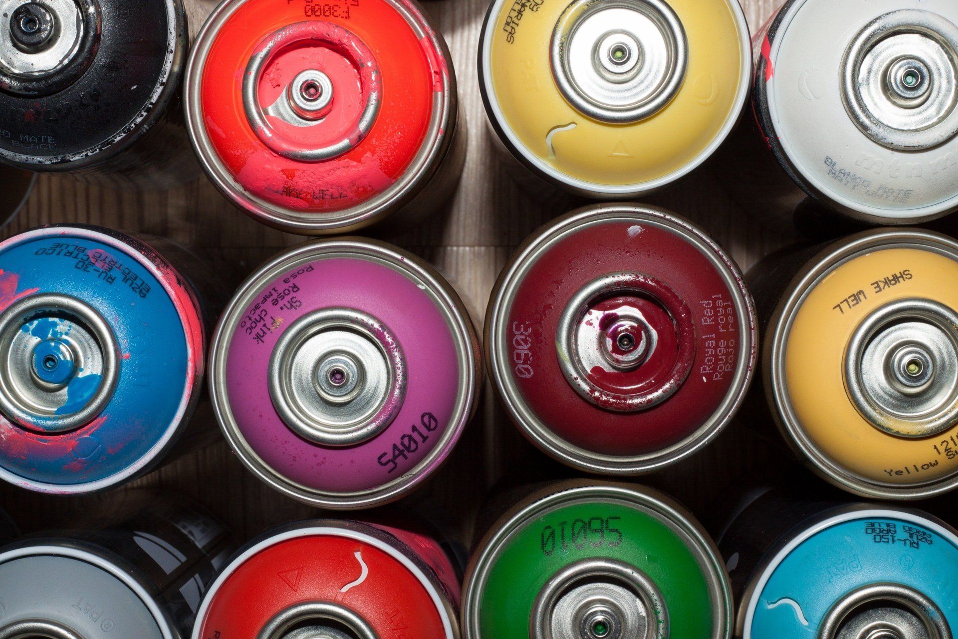 A bunch of spray paint cans are stacked on top of each other.